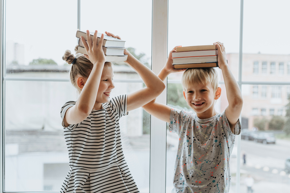 Canva - Brother and Sister With Books on Their Heads