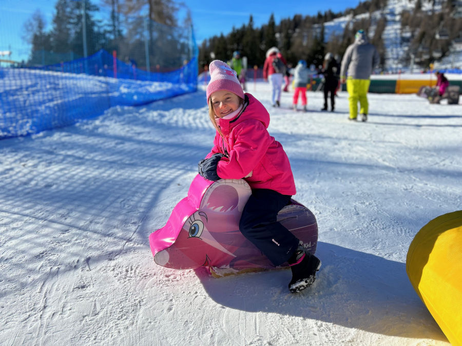 bambina sulla neve con cavalcabile morbido 